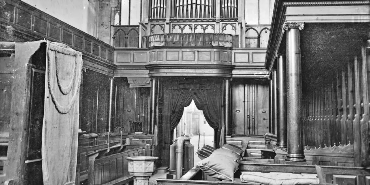 A black and white photograph of a church interior featuring a large pipe organ with intricate woodwork.